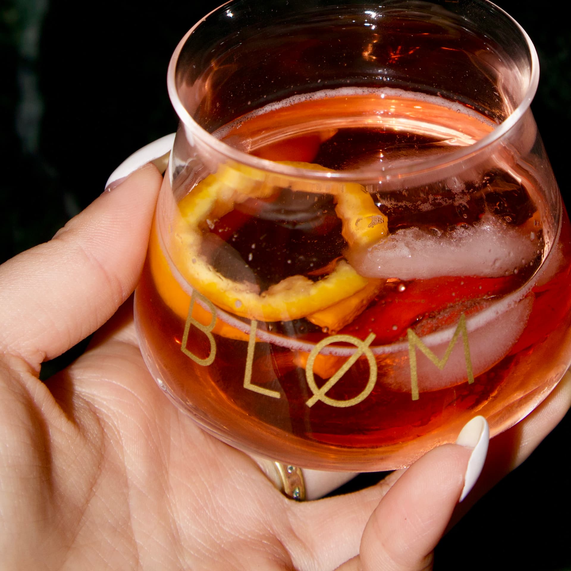 Hand holding a Bløm glass with citrus peel