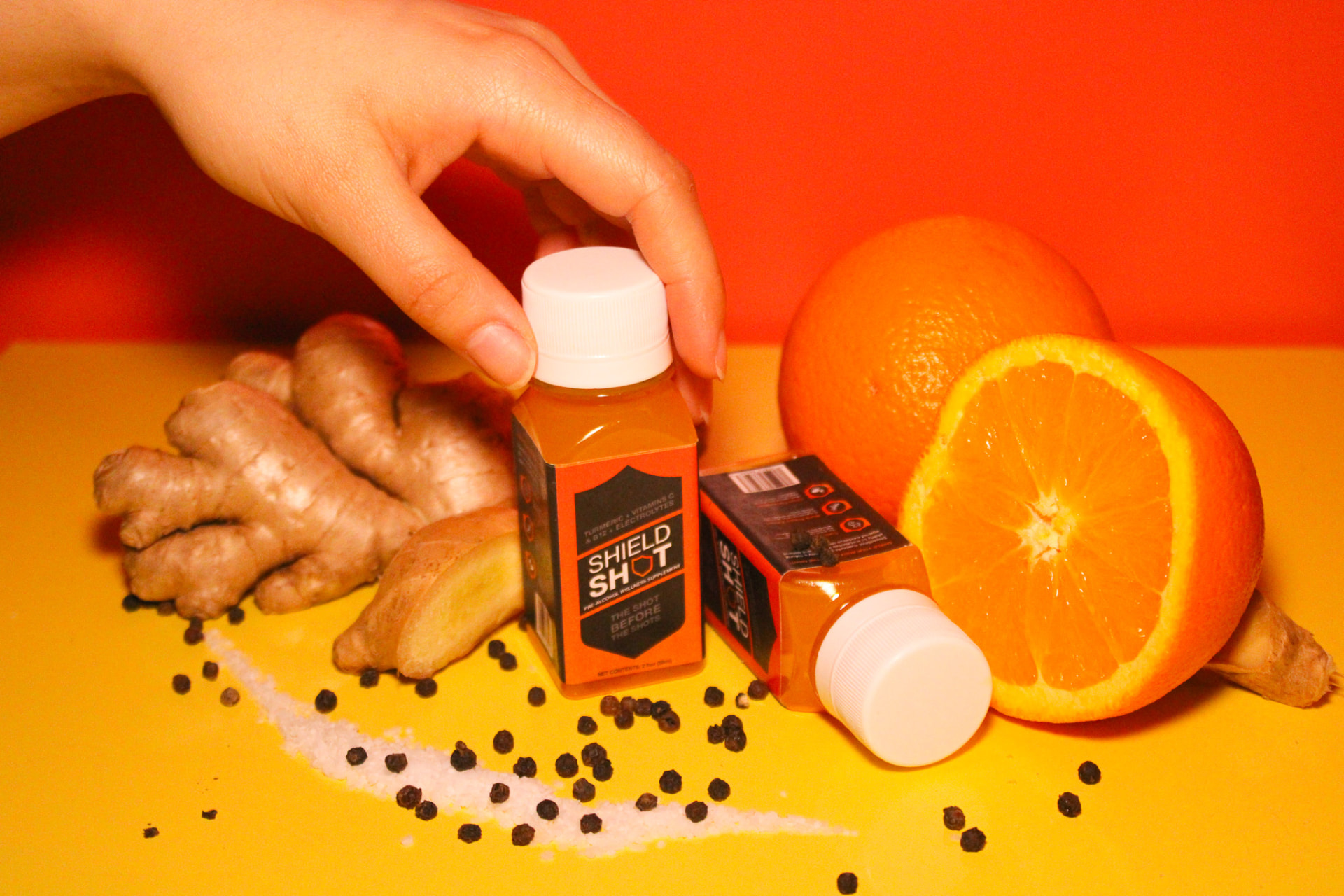 Hand placing a ShieldShot bottle in a styled set